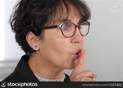 portrait of beautiful mature woman with finger on her lips
