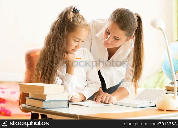 Portrait of beautiful mother helping daughter doing homework