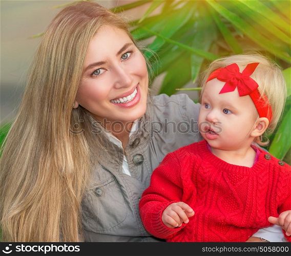 Portrait of beautiful mother with cute little daughter having fun in fresh green park, happy young family enjoying spring season