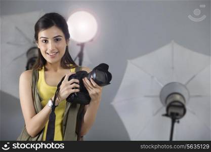 Portrait of beautiful photographer smiling with digital camera in studio