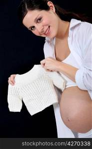 portrait of beautiful pregnant woman holding handknit pullover