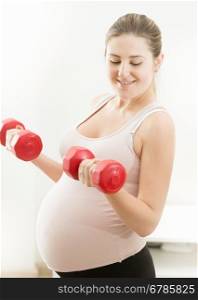 Portrait of beautiful pregnant woman lifting dumbbells