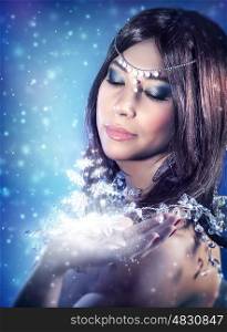 Portrait of beautiful princess looking on magical glowing light on her hand, Christmas miracle, fashion look for winter holidays