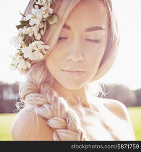 Portrait of beautiful romantic lady in a wreath of apple trees in the summer garden