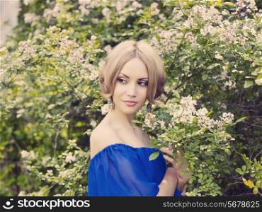 Portrait of beautiful romantic lady in the flowered garden