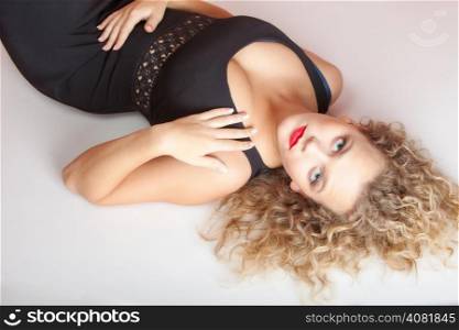 Portrait of beautiful sexy blonde girl lying on floor. Studio shot. Fashion and female beauty.