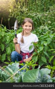 Portrait of beautiful smiling girl posing with trowel in garden. Beautiful smiling girl posing with trowel in garden