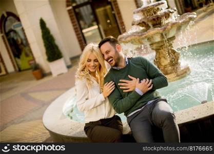 Portrait of beautiful smiling love couple sitting by fountain on a sunny day