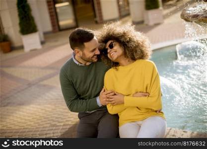 Portrait of beautiful smiling love couple sitting near fountain on a sunny day