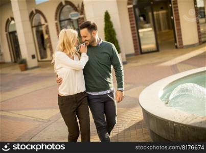 Portrait of beautiful smiling love couple walking by fountain on a sunny day