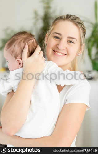 Portrait of beautiful smiling mother cuddling her 3 months old baby