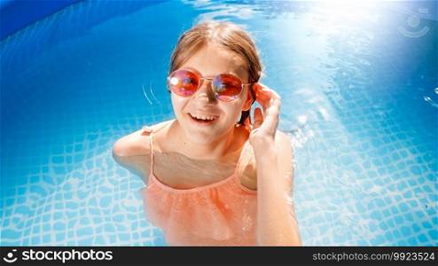 Portrait of beautiful smiling teenage girl in sunglasses and swimsuit relaxing in outdoor swimming pool. Concept of happy and cheerful summer holidays and vacation.. Portrait of beautiful smiling teenage girl in sunglasses and swimsuit relaxing in outdoor swimming pool. Concept of happy and cheerful summer holidays and vacation