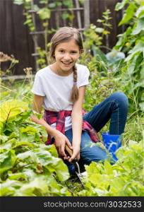Portrait of beautiful smiling teenage girl sitting in garden and spudding garden bed. Beautiful smiling teenage girl sitting in garden and spudding garden bed