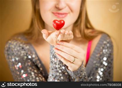 Portrait of beautiful smiling woman holding decorative red heart on hand