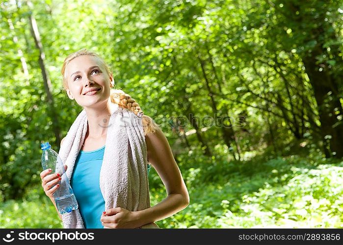Portrait of beautiful smiling woman with bottle of water after jogging
