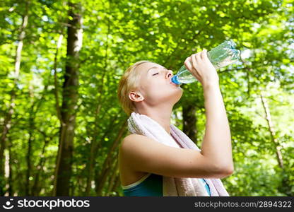 Portrait of beautiful smiling woman with bottle of water after jogging