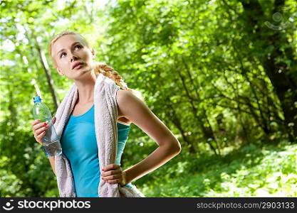 Portrait of beautiful smiling woman with bottle of water after jogging