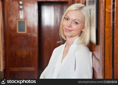 Portrait of beautiful smiling young blond woman resting her head against photo frame