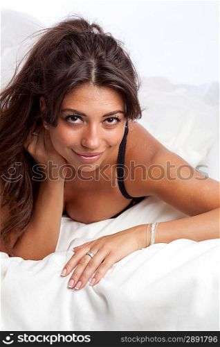portrait of beautiful smiling young woman lying in bed in her underwear.