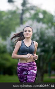 Portrait of beautiful sportswoman smiling away while running in park.Bokeh