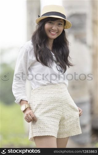 portrait of beautiful street fashion shot of asian younger woman wearing straw hat standing outdoor