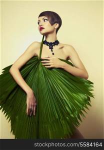 Portrait of beautiful stylish lady with palm leaves