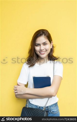 portrait of beautiful university student is smiling on yellow wall background