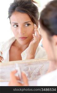 Portrait of beautiful woman applying anti-wrinkles cream