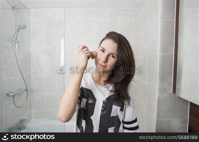 Portrait of beautiful woman applying makeup in bathroom