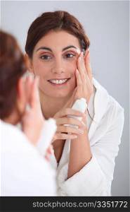 Portrait of beautiful woman applying moisturizer