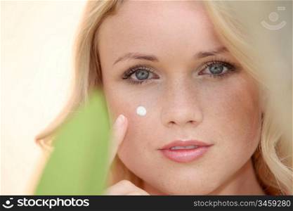 Portrait of beautiful woman applying moisturizer