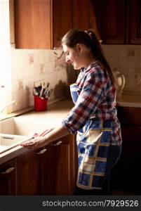 Portrait of beautiful woman cleaning kitchen with cloth