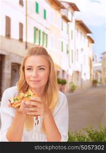Portrait of beautiful woman eating pizza outdoors in the restaurant in Italy, traditional Italian meal, tasty food, summer vacation concept