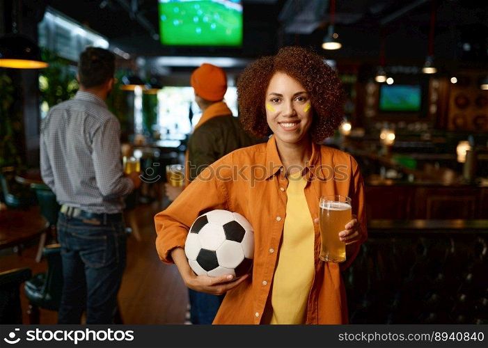 Portrait of beautiful woman football fan with creative makeup on face holding beer glass pint and looking in camera. Soccer match broadcasting in sports bar. Portrait of beautiful woman football fan with beer glass