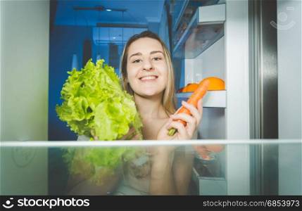 Portrait of beautiful woman holding carrot and fresh salad