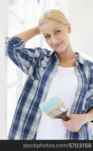 Portrait of beautiful woman holding paintbrush in new house