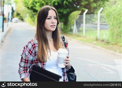 Portrait of beautiful woman holding paper coffee cup in the street. Urban city scene. Outdoors