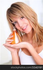 Portrait of beautiful woman holding scented lotion bottle