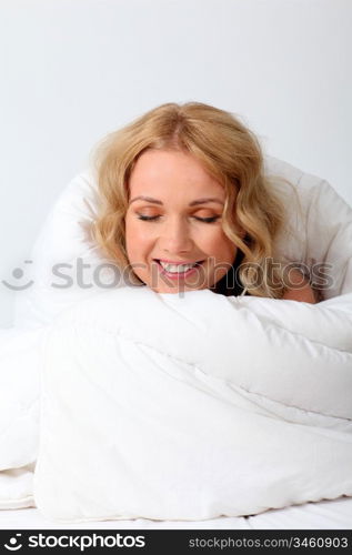 Portrait of beautiful woman in bed under blanket