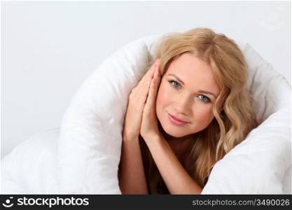 Portrait of beautiful woman in bed under blanket