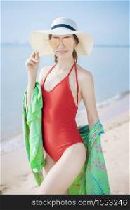 Portrait of beautiful woman in red swimsuit relaxing on the beach