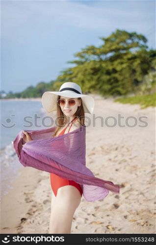 Portrait of beautiful woman in red swimsuit relaxing on the beach