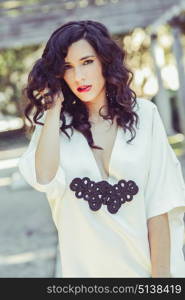 Portrait of beautiful woman, model of fashion, wearing white dress with curly hair