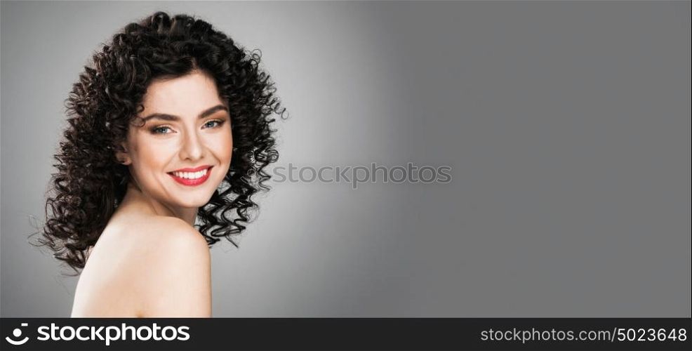 Portrait of beautiful woman. Portrait of amazing beautiful smiling woman with curly hair on gray background with copy space