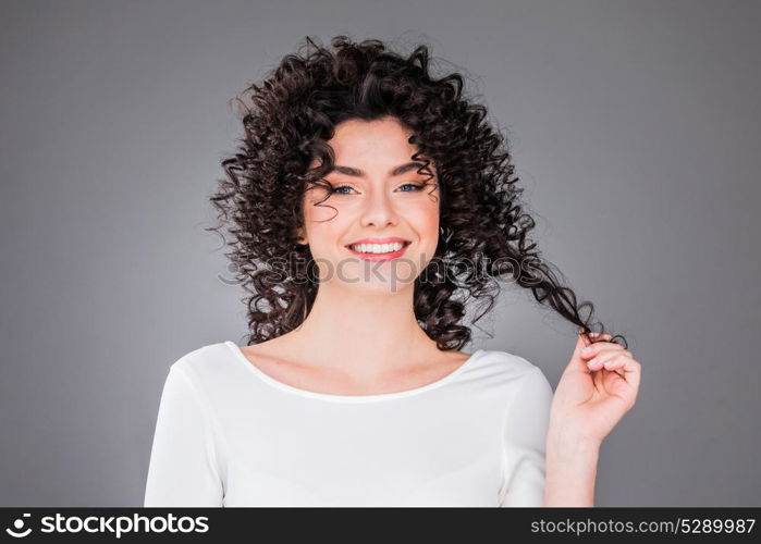 Portrait of beautiful woman. Portrait of amazing beautiful smiling woman with curly hair on gray background with copy space