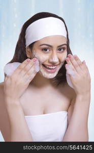 Portrait of beautiful woman scrubbing face with soap against blue background