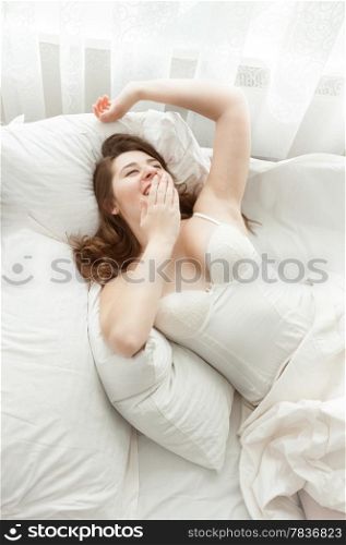 Portrait of beautiful woman stretching in bed