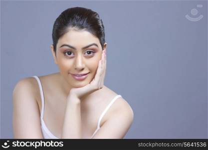 Portrait of beautiful woman with hand on chin over blue background
