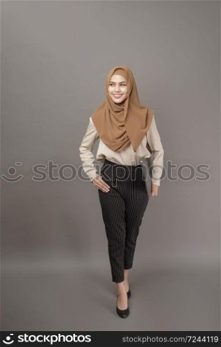 Portrait of beautiful woman with hijab is holding computer laptop on gray background