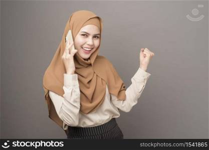 Portrait of beautiful woman with hijab using cellphone on gray background